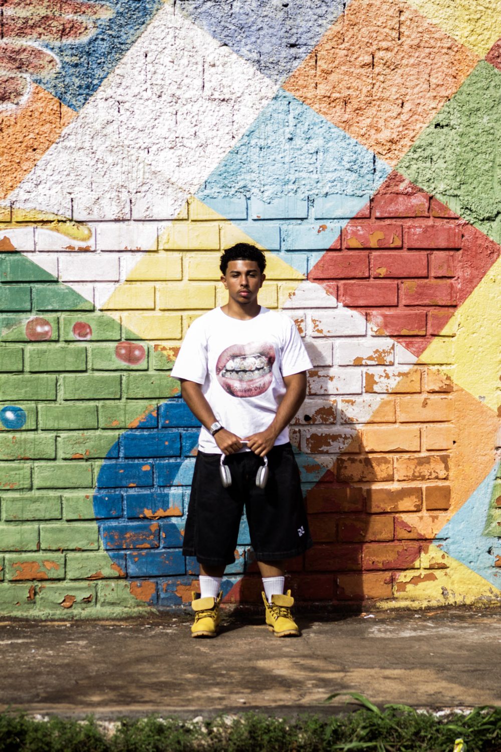 Feliphe diante do muro colorido, camiseta com estampa de boca